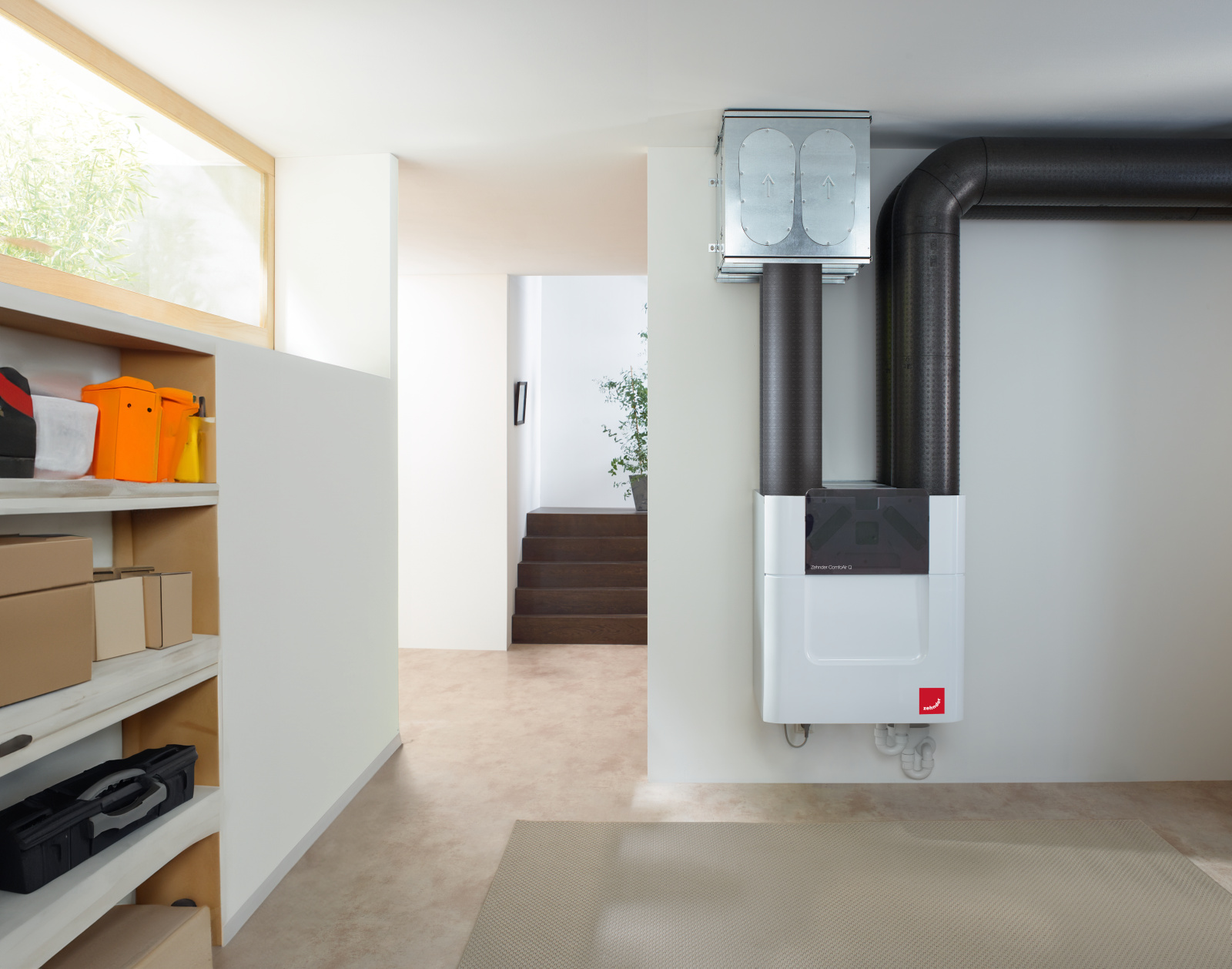 Kompaktní ventilační jednotka Zehnder s potrubím nainstalovaná v chodbě domu