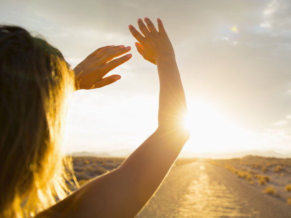 Hispanic woman shielding eyes from sun on remote road